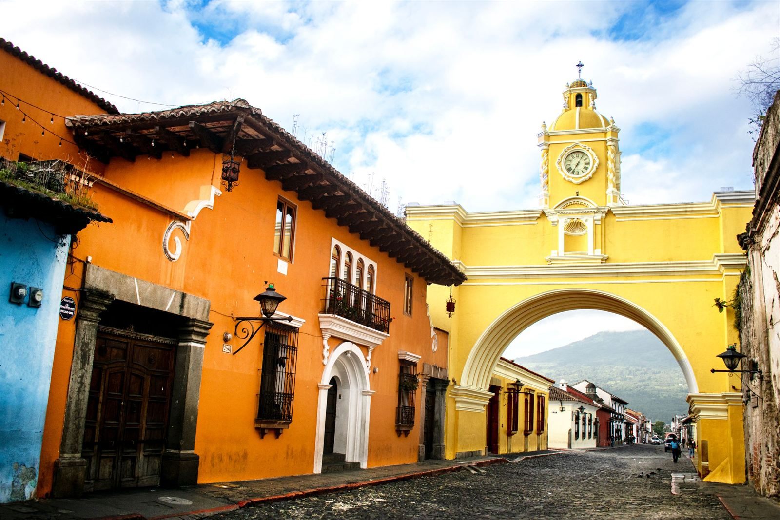 The yellow Santa Catalina Arch with its clock tower over a cobblestone street in Antigua Guatemala